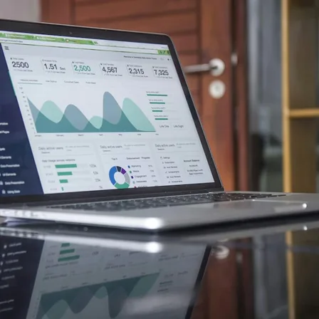 A laptop displaying a marketing analytics dashboard and performance charts.