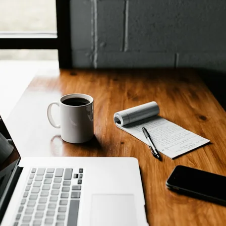 A laptop, notebook, and coffee arranged for a content planning session.